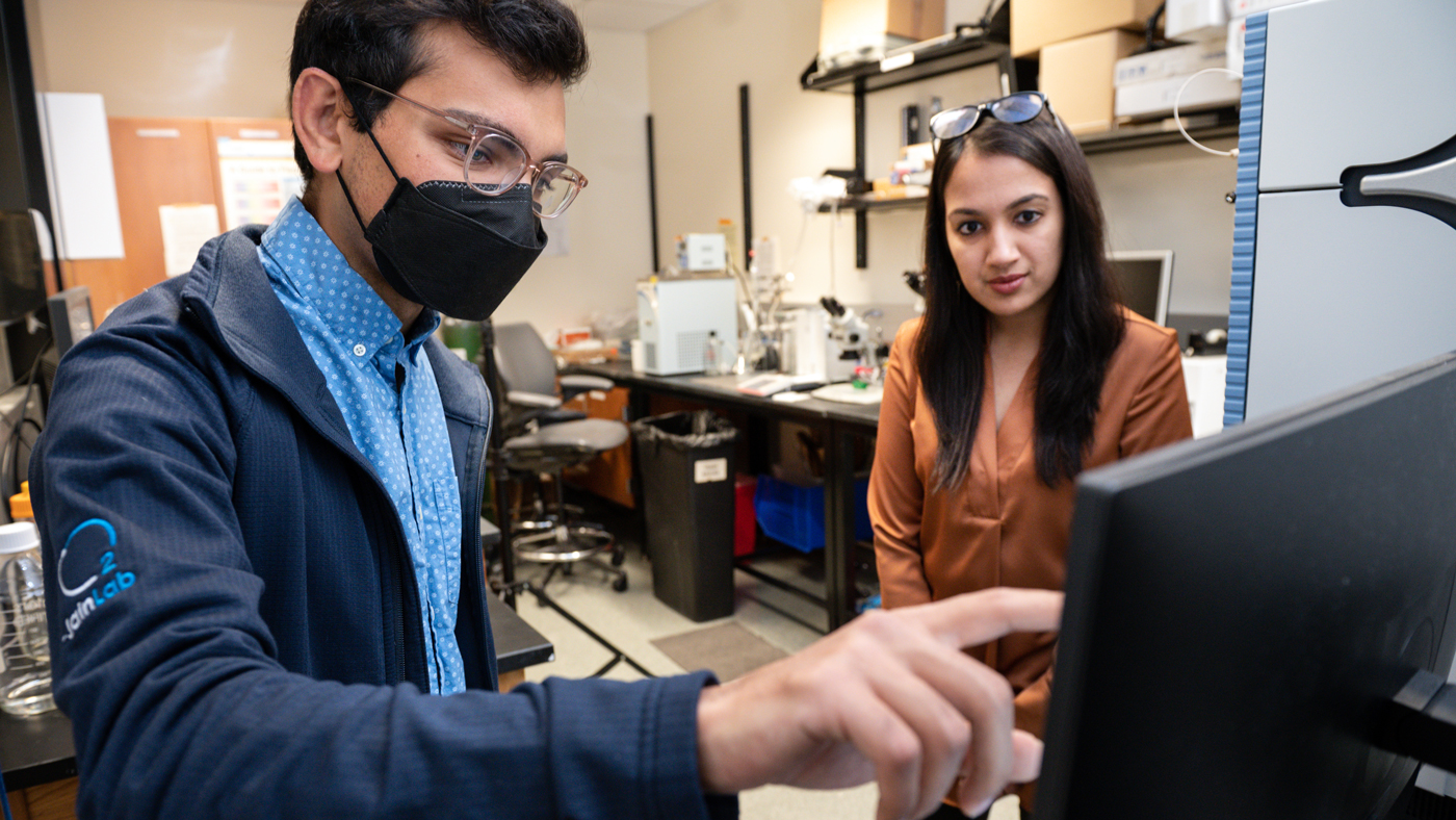Ayush Midha and Isha Jain look at data in the lab at Gladstone Institutes