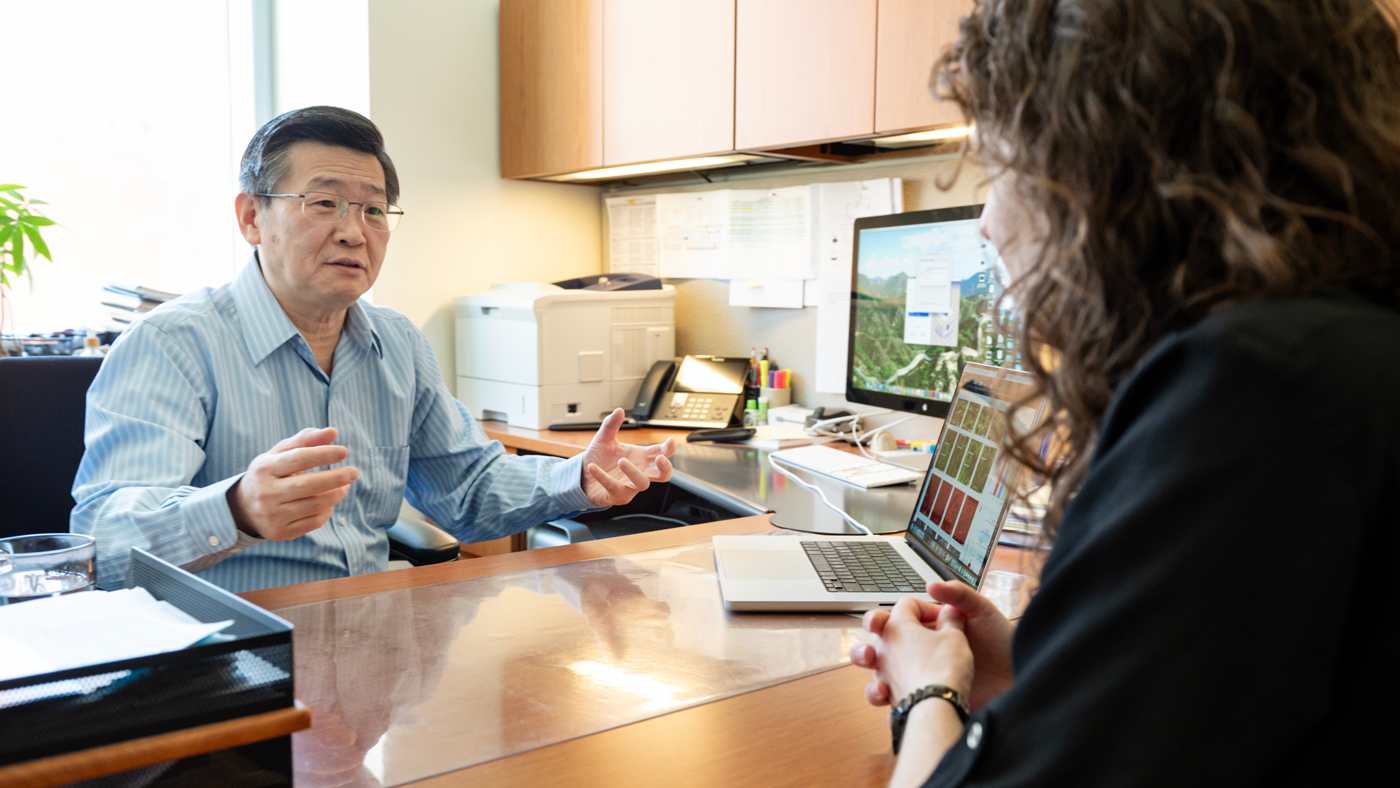 Yadong Huang speaking to a scientist in his lab