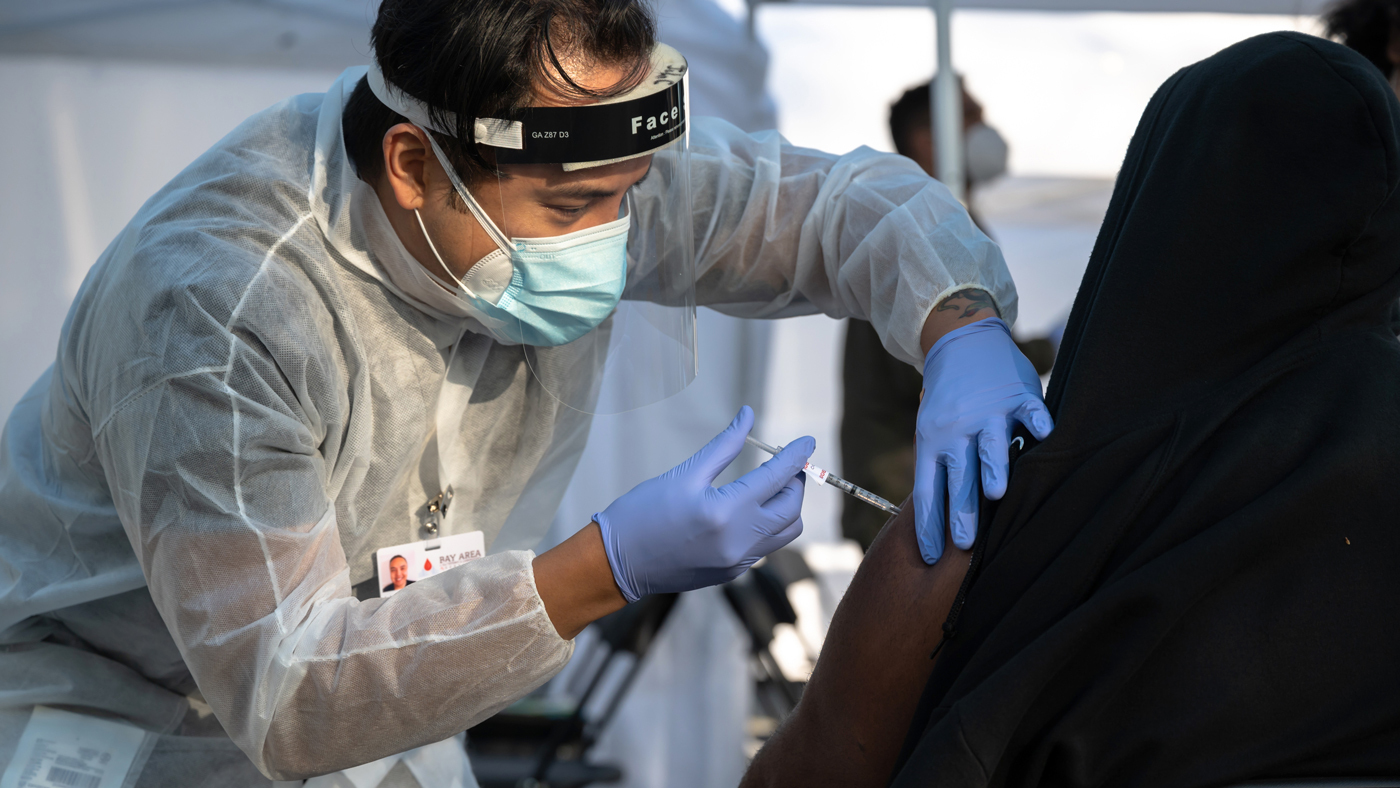 UCSF contractor vaccinates a patient at a drive-through pop up community vaccination site