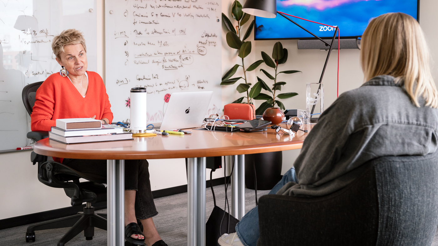 Melanie Ott sitting at her desk speaking to someone sitting across from her