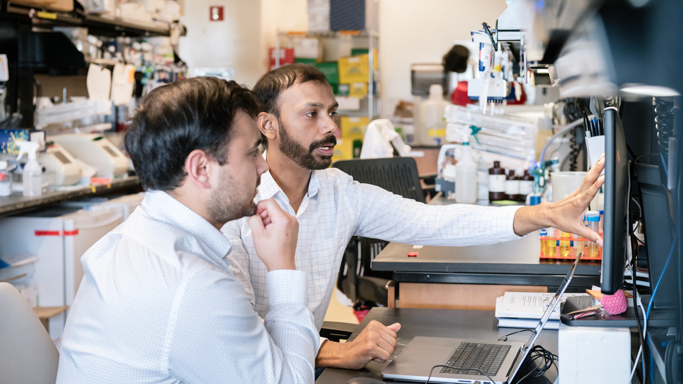 Ujjwal Rathore and Eli Dugan looking at a monitor in the lab at Gladstone Institutes