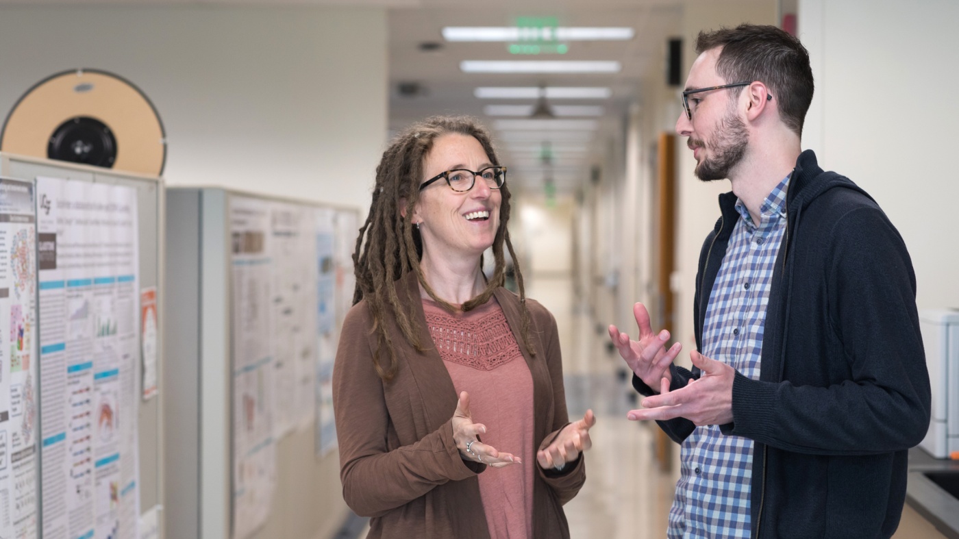 Katie Pollard talking with a scientist in the hall